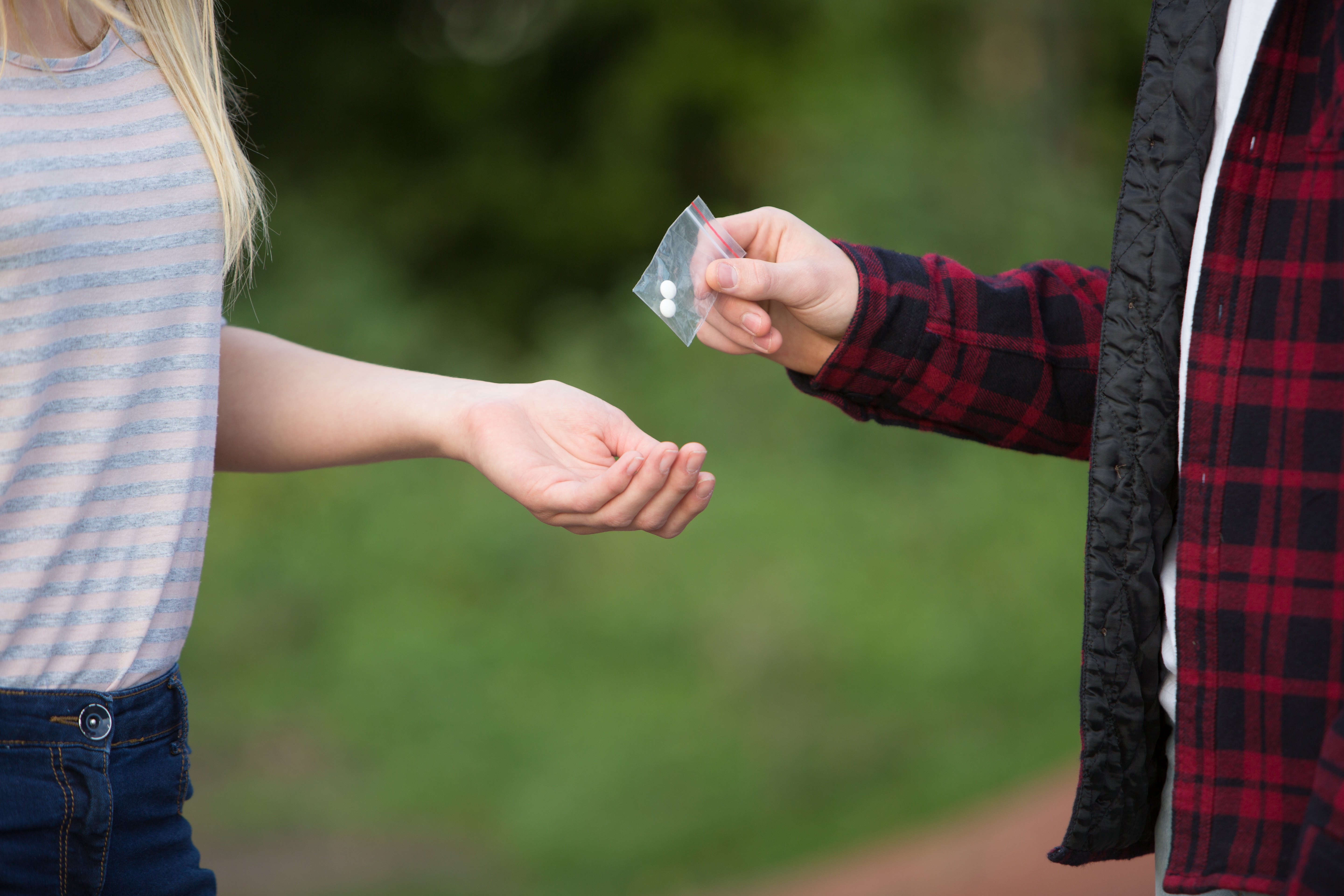 A teenage girl buying drugs from a boy outside school, photo by Daisy-Daisy/Getty Images