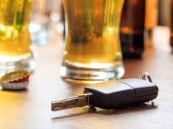 Car key on a wooden bar counter next to a glass of beer. Photo by Rawf8/Adobe Stock