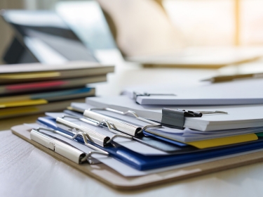Stack of clipboards and documents on a desk, photo by juststock / Getty Images