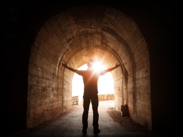 Man stands inside of old dark tunnel, photo by evannovostro/Adobe Stock