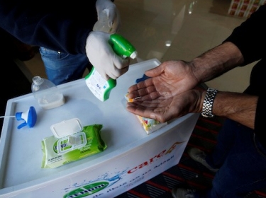 A Palestinian worker sanitizes the hands of a customer at a supermarket in Gaza City, March 8, 2020. Picture taken March 8, 2020, photo by Mohammed Salem/Reuters