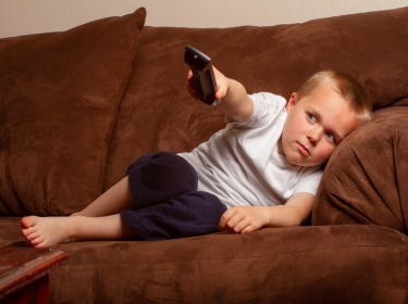 Lazy boy on couch watching TV, photo by Tracy King/Adobe Stock