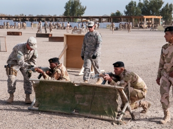 U.S. soldiers assist Iraqi army trainees on setting into the proper kneeling firing position during movement technique training on Camp Taji, Iraq, January 7, 2015
