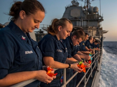 Sailors aboard the USS San Jacinto pray for suicide victims during a suicide prevention and awareness event called Walk Out of Darkness