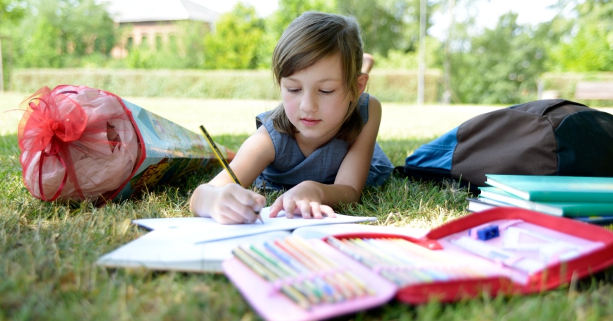 Girl doing homework outside on the grass
