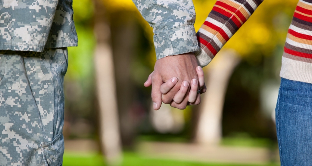 A servicemember and his wife hold hands