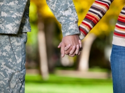 A servicemember and his wife hold hands