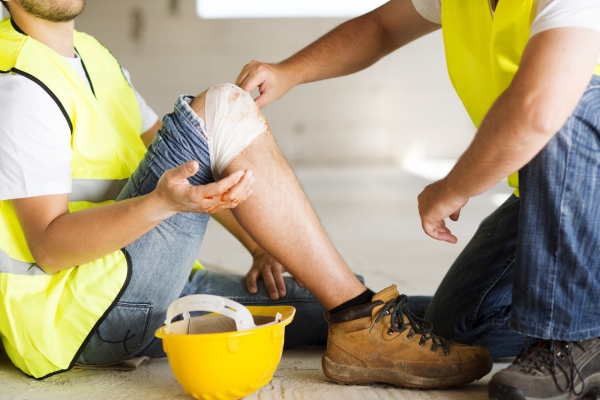 A construction worker getting his knee bandaged onsite