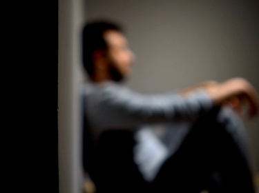 Out-of-focus image of a man sitting against a wall, photo by Vilin Visuals / Getty