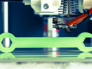 A 3D printer making a wrench with bright green filament, photo by wsf-f/Adobe Stock