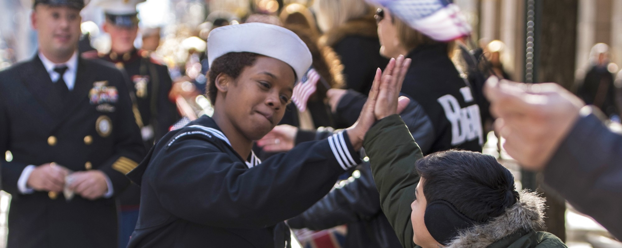 Navy Petty Officer 3rd Class Zatyra Rousseau high-fives a child during the 2018 Veterans Day Parade in New York City, Nov. 11, 2018.