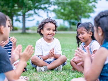 Children playing hand games in the grass