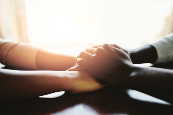 Closeup shot of two people holding hands in comfort, photo by PeopleImages/Getty Images