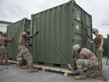 Seabees chain a container to a pallet