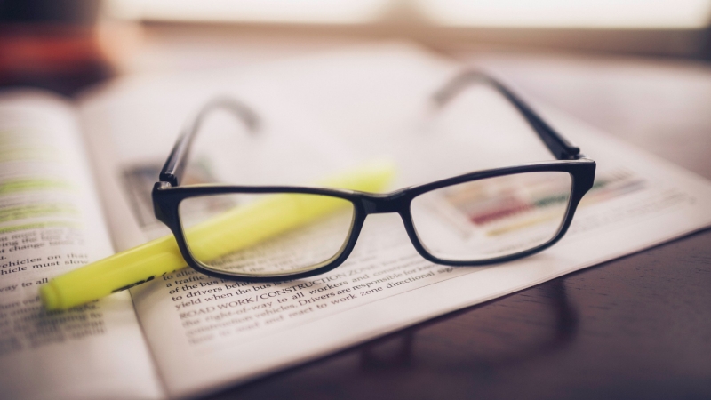Glasses and yellow highlighter on top of a magazine