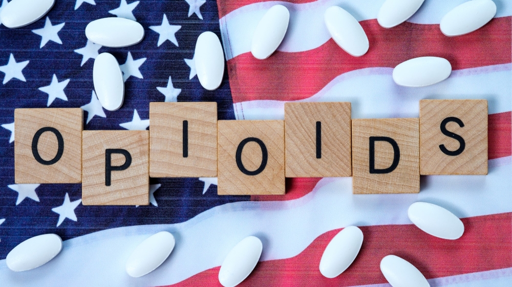 Tiles spelling out "opioids" and pills scattered on top of the American flag