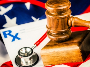 Prescription pad, stethoscope, and gavel on top of the American flag