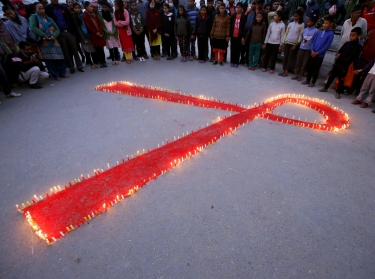People gather around candles in the shape of an AIDS awareness ribbon ahead of World AIDS Day, in Kathmandu, Nepal, November 30, 2016