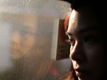 Close up of a woman looking out a window, photo by Lewis Tse Pui Lung/Adobe Stock