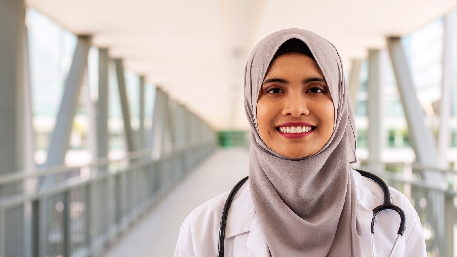 Portrait of confident Muslim doctor wearing hijab standing at the entrance of hospital, photo by gahsoon/Getty Images
