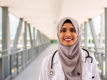 Portrait of confident Muslim doctor wearing hijab standing at the entrance of hospital, photo by gahsoon/Getty Images