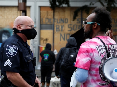 Seattle Police officer Robert Brown talks with protesters as other officers collect evidence at the CHOP (Capitol Hill Organized Protest) area after a fatal shooting as people occupy space in the aftermath of the death in Minneapolis police custody of George Floyd, in Seattle, Washington, U.S. June 29, 2020.
