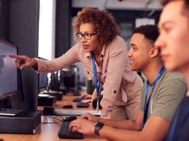 Group of college students with tutor studying computer design sitting at monitors in classroom, photo by Monkey Business Images/Adobe Stock