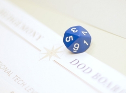 A blue die sits atop a rule sheet for Hedgemony during a demonstration of gameplay.