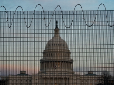 Barbed wire and protective fencing surrounds the U.S. Capitol, as the sun sets in Washington, February 21, 2021, photo by Al Drago/Reuters