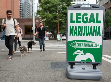 People passing a State Legal Marijuana shop sign on 2nd avenue late in the day in downtown Seattle, WA, July 14, 2016