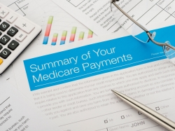 Medicare payments summary with paperwork, photo by courtneyk/Getty Images