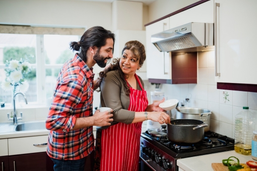 TAn adult son watches his mother cook