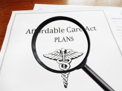 Magnifying glass over papers titled Affordable Care Cat Plans, photo by zimmytws/Getty Images