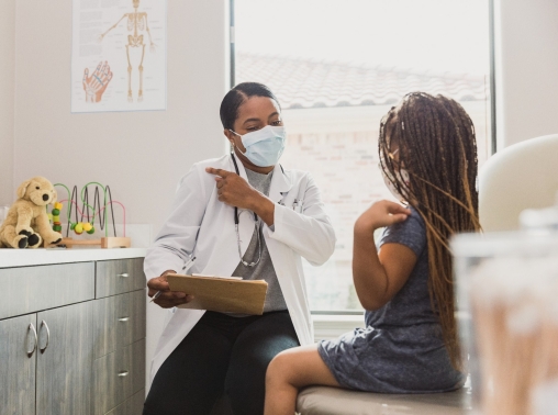 A Black female pediatrician talks to a Black female patient in the exam room