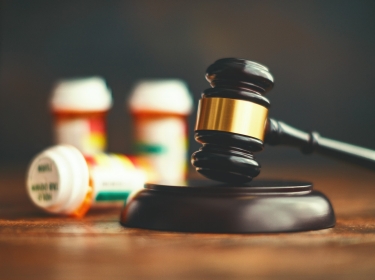 A judge's gavel with bottles of prescription drugs. Photo by CatLane/Getty Images