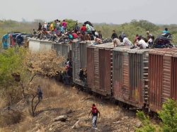 Mexican migrants migrants clamber atop a freight train bound for the U.S.-Mexican border