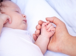 mother holding newborn baby's hand