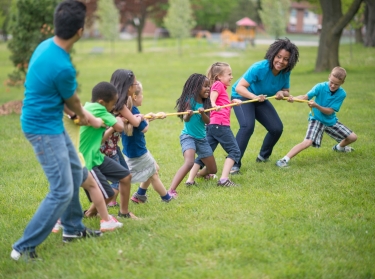 Adults and children playing tug of rope in a neighborhood park