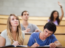 Students taking notes while their classmate raises her hand