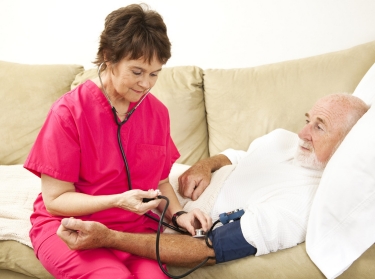 A home health nurse checking man's blood pressure