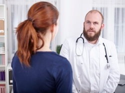 A doctor looks distracted while talking to a patient