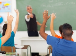 A gorup of students with hands up in the classroom