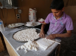 A boy makes pastry at a shop in Darkush town, Idlib countryside, Syria, May 26, 2013