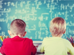 Two children face the blackboard in a classroom