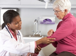 Doctor examining female senior patient with elbow pain