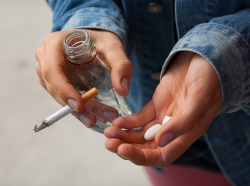 girl holding vodka, pills, and cigarettes