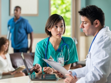 Nurse talking to doctor about patient in busy waiting room