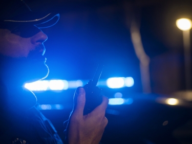 Police officer radioing for backup, photo by karrastock/Adobe Stock