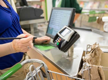 Woman using credit card machine at grocery store check out