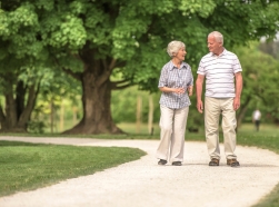 Two older adults walking in a park